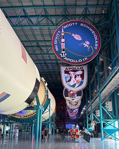Eine riesige Saturn-V-Rakete liegt in einer Ausstellungshalle des Kennedy Space Centers unter großen Apollo-Missionsemblemen.