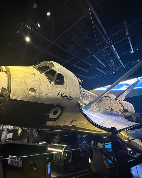 Die echte Raumfähre Space Shuttle Atlantis mit geöffneter Ladebucht in der dunklen Ausstellungshalle des Kennedy Space Centers.