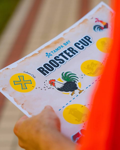 Hände halten eine Schatzkarte für den „Tampa Bay Rooster Cup“ mit einem Hahn-Motiv und einer Markierung für den „Cuban Club“.