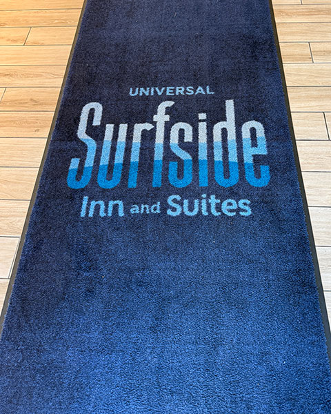 Ein langer blauer Teppichläufer mit dem Logo „Universal Surfside Inn and Suites“.