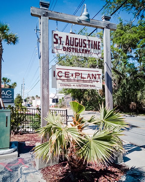 Schild miot dem Schriftzug St. Augustine Distillery sterht hinter einer Pflanze.